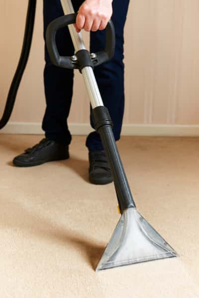 This is a photo of a man steam cleaning a cream carpet, using a professional steam cleaning machine works carried out by Worcester Park Carpet Cleaning