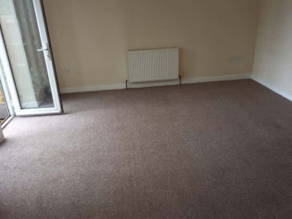 This is a photo of a living room after it has been cleaned. The room is empty and has a brown carpet that has been steam cleaned works carried out by Worcester Park Carpet Cleaning